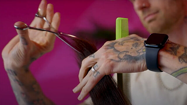 Man cutting a client's hair. Close up of the hand holding scissors.