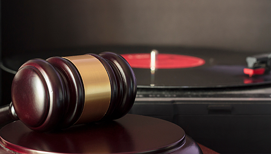 A gavel in front of an album on a record player.