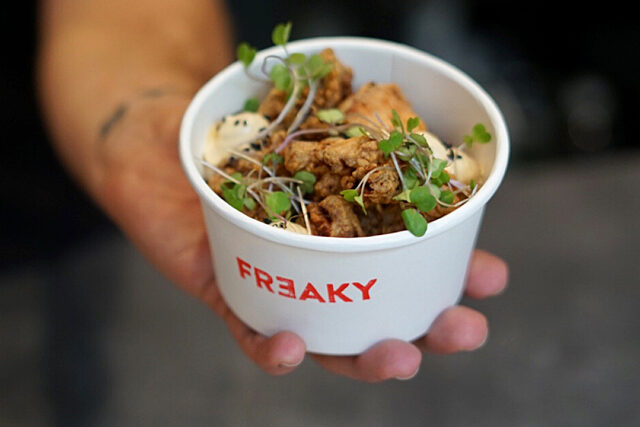 Hand holding a small paper cup of fried food