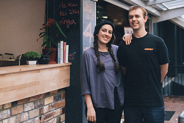 Two people standing outside of a cafe on the footpath